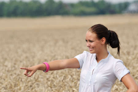 attractive young woman pointing at something in summerの写真素材