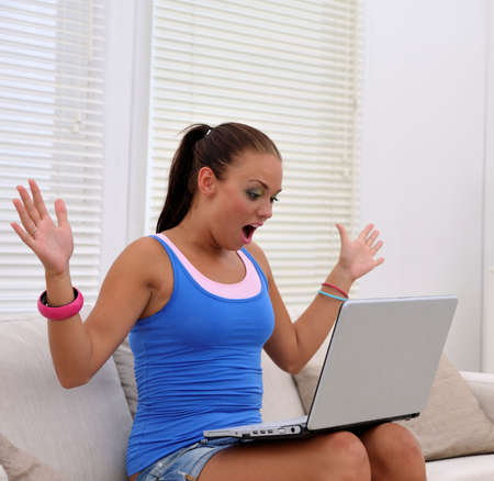 young attractive woman surprised about something on her notebookの写真素材