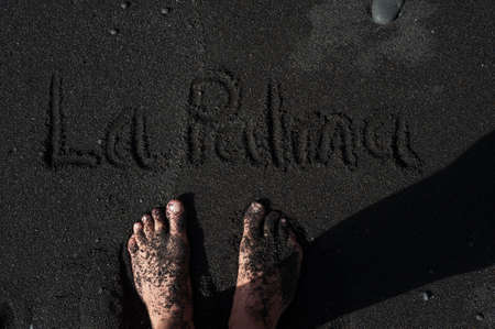Feet standing on a black sand beach of La Palma, Canary islands, Spainの写真素材