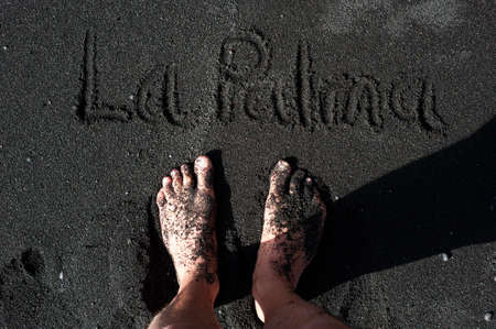 Feet standing on a black sand beach of La Palma, Canary islands, Spainの写真素材
