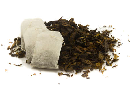 three tea bags over dried tea leaves backgroundの写真素材