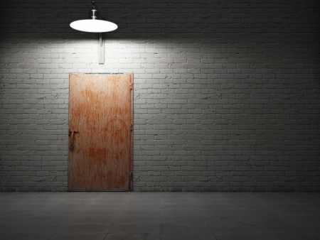Dirty brick wall illuminated by lamp with rusty metal doorの写真素材