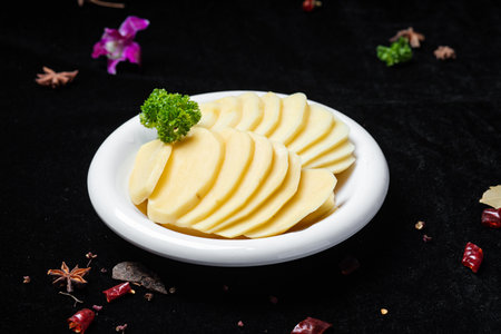 Sliced Cheese on a Black Background with Herbsの写真素材