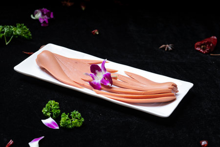 Slices of meat on a white plate on a black backgroundの写真素材