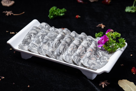 Dried fish sashimi in a white plate on a black backgroundの写真素材