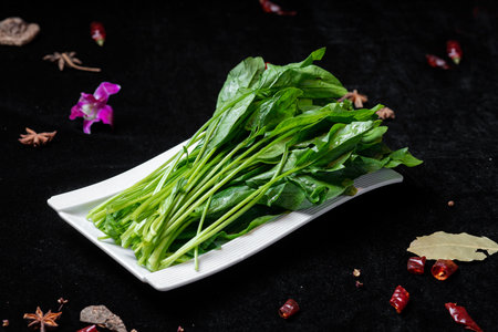 Fresh green leaves on a white plate on a black backgroundの写真素材