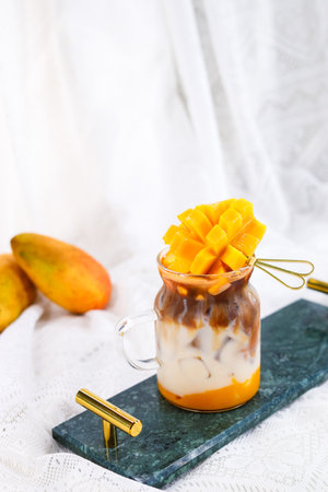 Mango dessert with yogurt in a glass jar on a light backgroundの写真素材