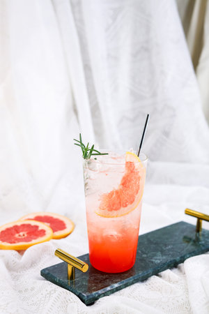 Grapefruit cocktail with ice and rosemary on a white backgroundの写真素材