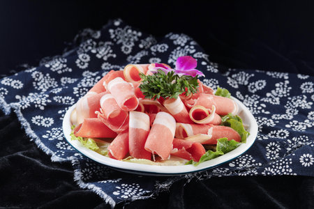 Sliced jamon with lettuce and parsley on black backgroundの写真素材