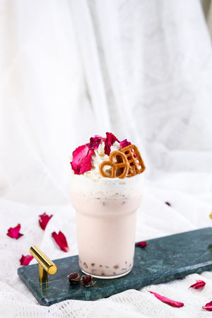 Milkshake with whipped cream and rose petals on white backgroundの写真素材