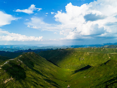 Aerial view of green mountains under blue sky with white clouds.の写真素材