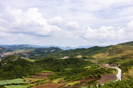 Mountain landscape with green hills, blue sky and white clouds.の写真素材