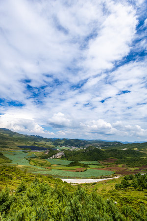 Beautiful mountain landscape with green hills and blue sky with white cloudsの写真素材