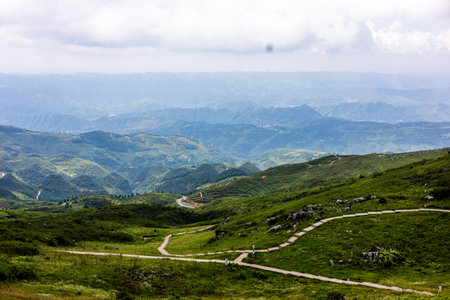 Landscape view of green mountain meadow with road and clouds.の写真素材