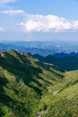 Mountain landscape with green grass and blue sky.の写真素材