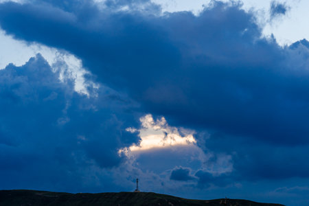 Clouds in the blue sky with a tower on the hillの写真素材