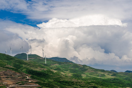 Wind turbines generating electricity on the hillside with cloudy sky background.の写真素材