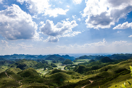 Panoramic view of green hills and blue sky with white cloudsの写真素材