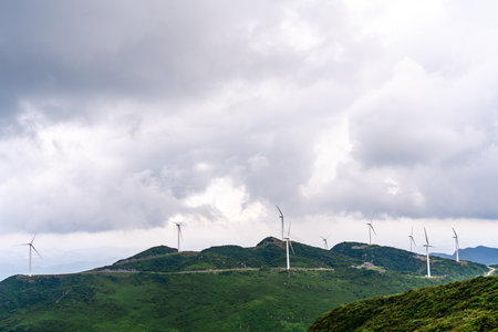 Wind turbines in the mountains under a cloudy sky.の写真素材
