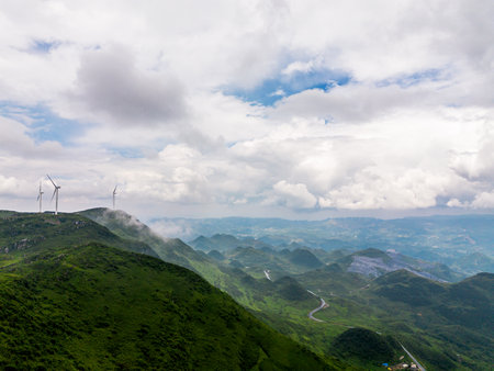 wind turbines on the top of mountain under blue sky with white cloudsの写真素材
