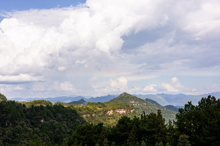 Mountain landscape with cloudy sky and rainbow in Yunnan, China.の写真素材