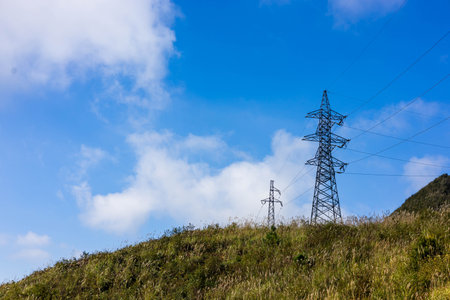 High voltage power line on the hill with blue sky background, power transmission conceptの写真素材