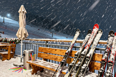 Skis on a bench in the mountains during a snowfall.の素材