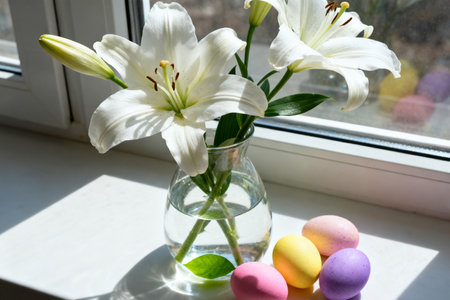 Easter eggs and white lily flowers on the windowsill.の素材