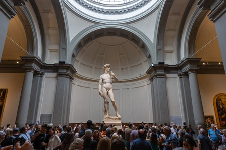 Florence,Italy-10:25:2023:Masterpiece of David of Italian sculpture in Accademia Gallery people gathered to watch background blur bokeh noise selective focusのeditorial素材