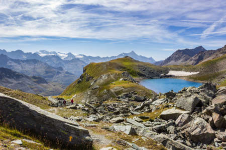Hiking trail in Cogne valley, Aosta, Italy. Lake of Pontonnet in the high walloon of Urtier at 2800 meters of altitude. Two hikers are walking.の写真素材
