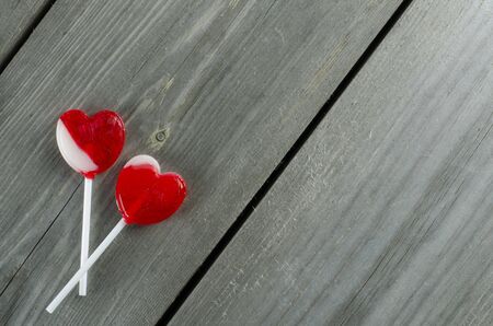 Red heart-shaped  lollipops candies on wooden surface with free spaceの写真素材