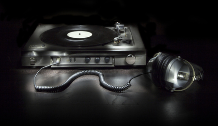 Old turntable with headphones isolated on a black background