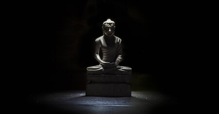 Buddha statue on a table isolated on a black backgroundの写真素材