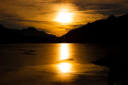 Frozen mountain lake during sunset on a cloudy dayの写真素材