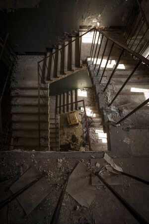 Concrete stairs illuminated with a picturesque light in an abandoned building in a sunny day. The light enters through some windowsの写真素材