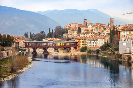 Bridge Ponte degli Alpini at river Brenta in Bassano del Grappa, Italy. Panoramic view at old town with vintage building and wooden bridgeのeditorial素材