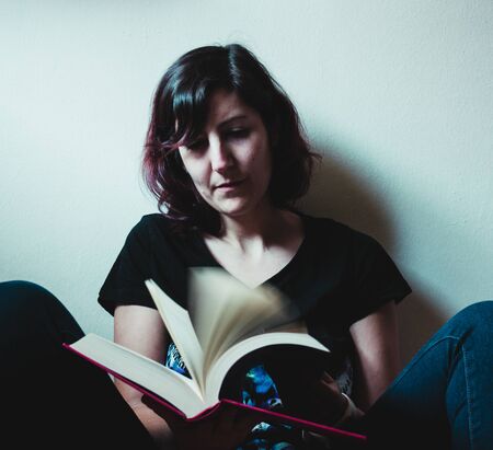 Woman reading a book with soft-light during quarantine time.の写真素材