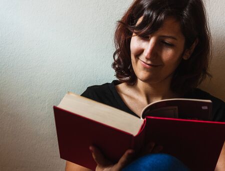 Woman reading a book during quarantine time with a smile.