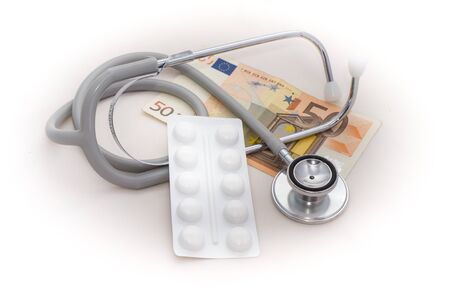cost of health care represented by a stethoscope with money and a blister pack of drugsの写真素材