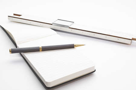 Vintage Desk with old and used slide rule, block notes and pen isolated on white backgroundの写真素材