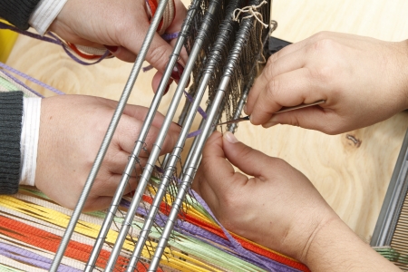 two persons working on loom
