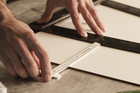 close-up of hands of a joinery while measuring and marking the wood that will workの写真素材