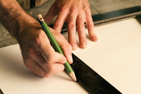 close-up of hands of a joinery while measuring and marking the wood that will workの写真素材