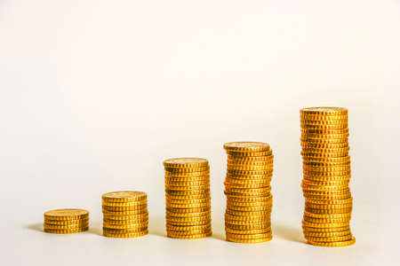 Yellow coins lined up from short to tall stacks with white backgroundの写真素材