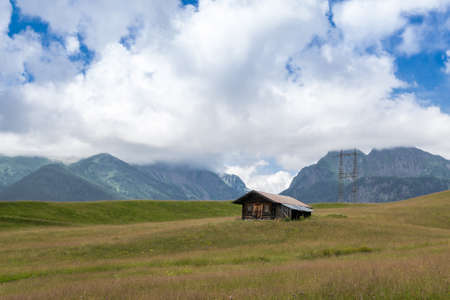 wooden house in a green meadow near mountainsのeditorial素材