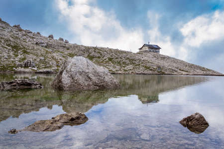 Italian Alps in Val Badia, Reflection of a mountain shelter in a lakeの写真素材