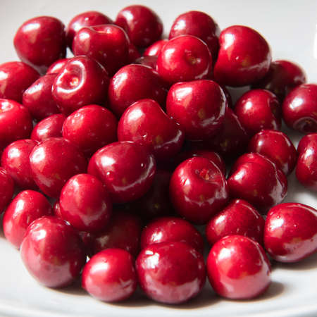 Bowl of red fresh cerries on a white backgroundの写真素材
