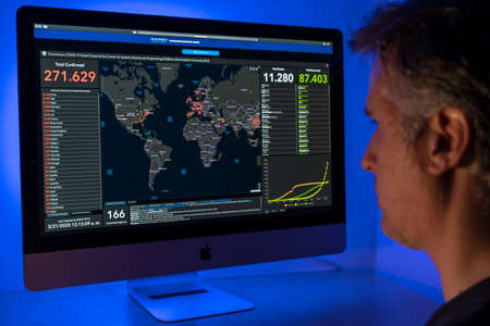 A man looks at Coronavirus global cases at his computer. The screen shows the website of the Coronavirus Resource Center at Johns Hopkins University. The Center for Systems and Engineering at Johns Hopkins Univerity has developed a world map showcasing thのeditorial素材