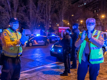 Two emergency paramedics clap their hands to show their support to hospital healthcare workers fighting coronavirus pandemic. Everyday, at 8pm, paramedics and several police patrols gather at the main entrance of the FundaciÃ³n JimÃ©nez DÃ­az hospital in のeditorial素材