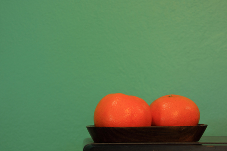 Two oranges on wood tray againts retro green paint wallの写真素材